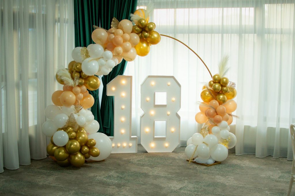 Số 18 phát sáng giữa vòm bóng bay trắng và vàng
